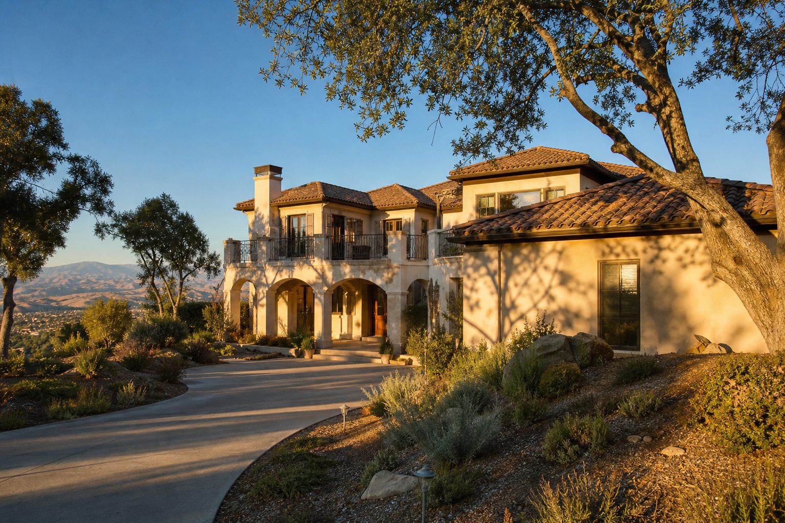 Mediterranean luxury home with clay tile roof on hilltop lot in Stevenson Ranch with mature oak trees and valley views.