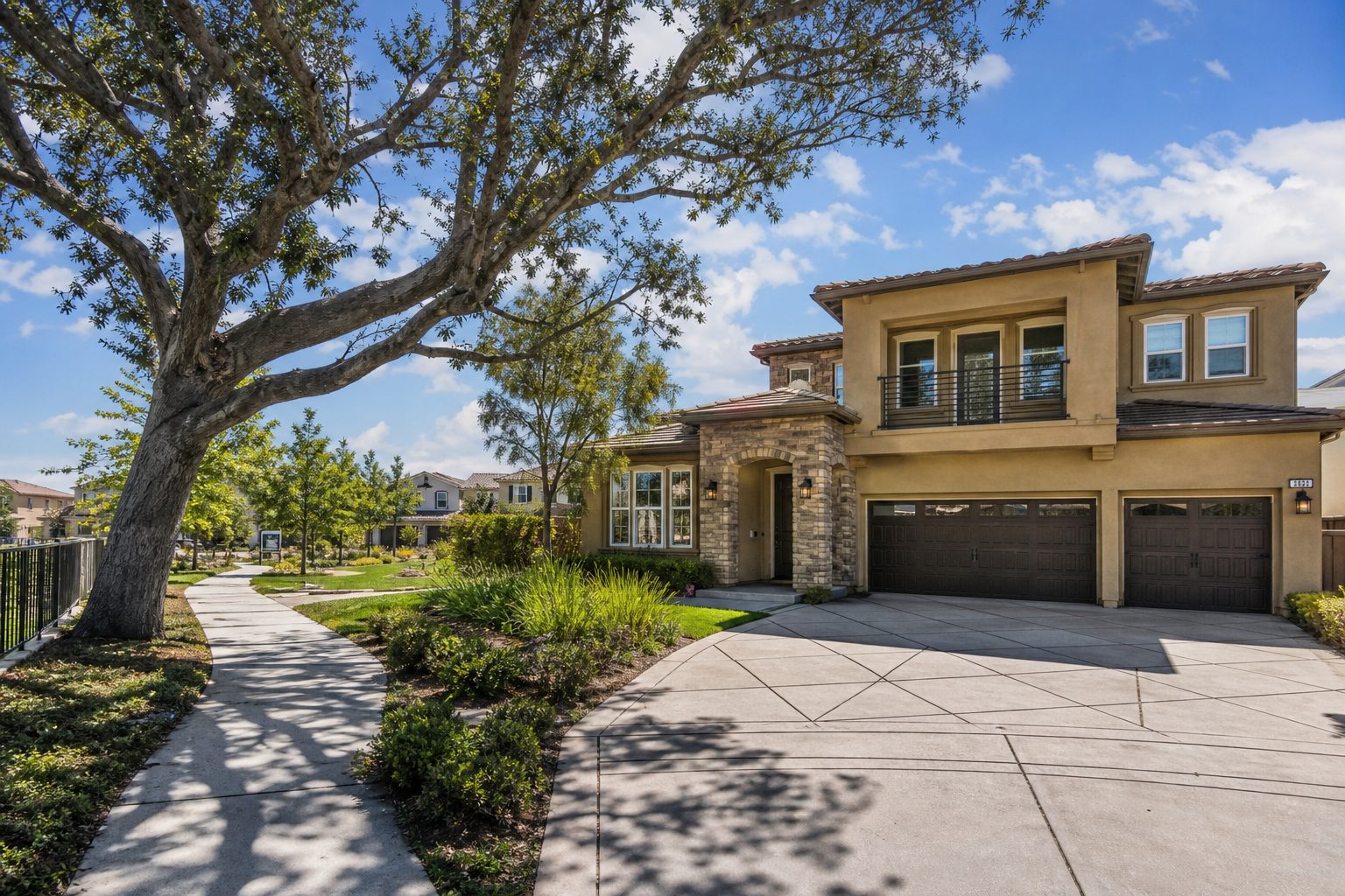 Two-story contemporary home in Valencia with mature oak tree, wide driveway, and pedestrian trail system visible in neighborhood setting.